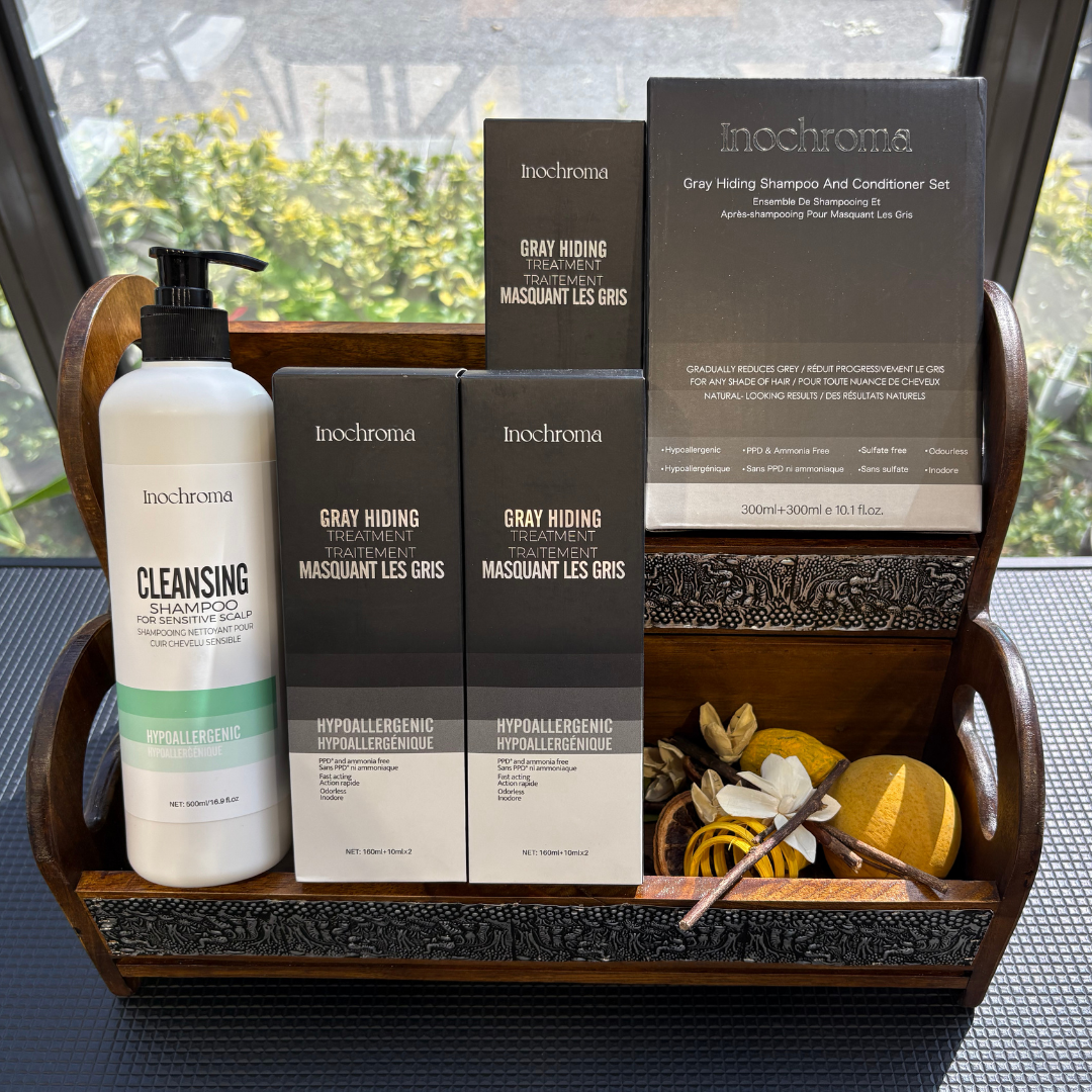 Inochrome hair care products including bottles and boxes on a wooden tray with a blurred outdoor background.