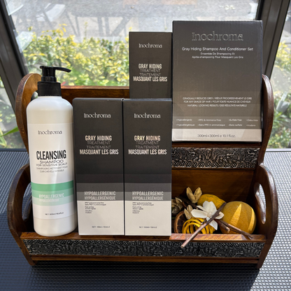 Inochrome hair care products including bottles and boxes on a wooden tray with a blurred outdoor background.