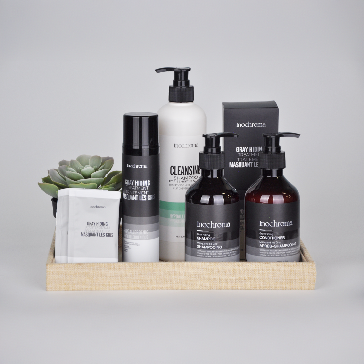 Set of Inochroma hair care products including bottles and a box on a gray background